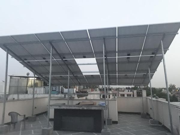 Elevated solar canopy on tall steel columns over a tiled rooftop terrace at dusk