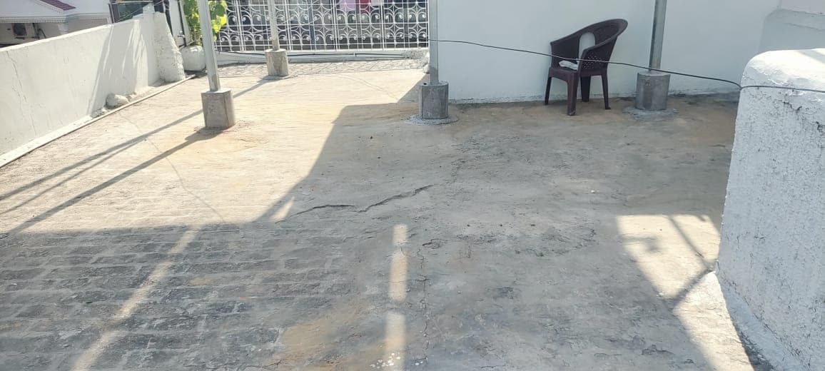 Empty rooftop terrace with steel posts set in concrete footings, a plastic chair and an iron railing
