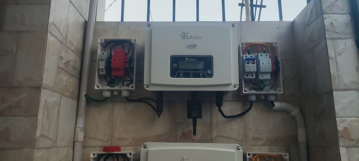 K Solare inverter mounted on a stone-tiled wall between DC and AC distribution boxes