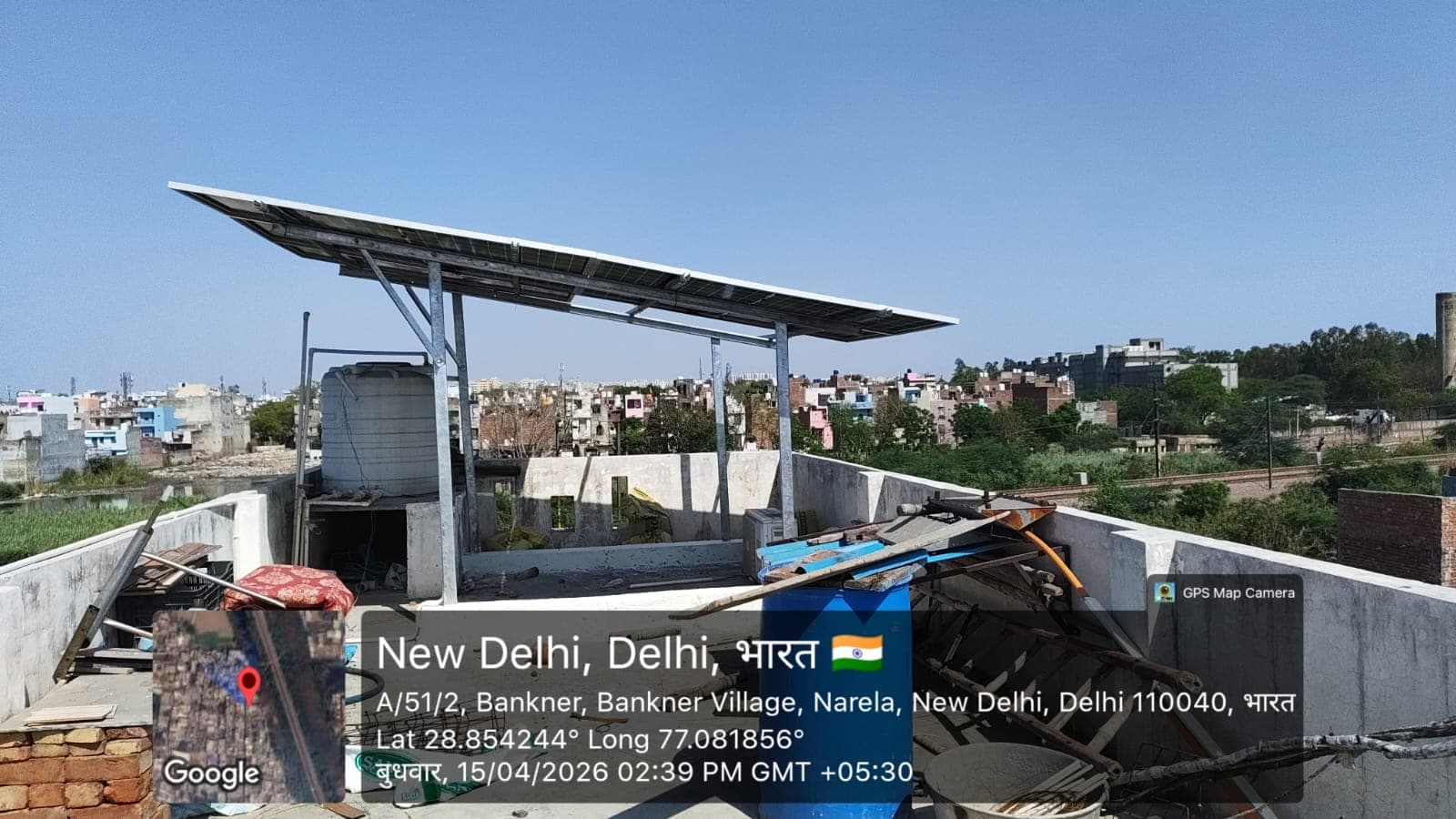Elevated solar panels on galvanised posts above a rooftop under construction with a wide town view in New Delhi